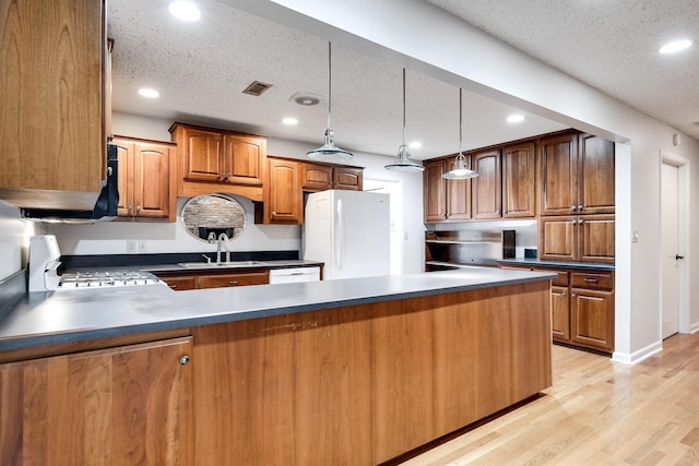 kitchen with sink, white appliances, light hardwood / wood-style floors, a textured ceiling, and decorative light fixtures