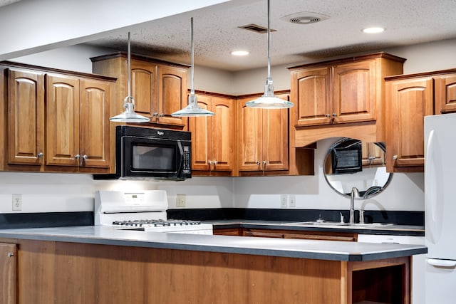 kitchen featuring hanging light fixtures, sink, a textured ceiling, and white appliances