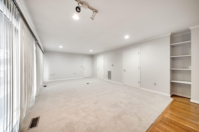 unfurnished room featuring rail lighting, light carpet, and crown molding