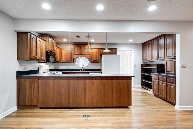 kitchen featuring pendant lighting, kitchen peninsula, white appliances, and light hardwood / wood-style floors