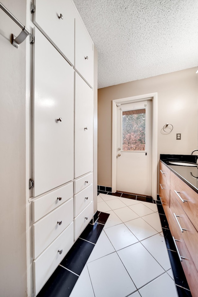 bathroom with tile patterned floors, sink, and a textured ceiling