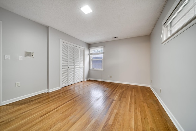 unfurnished bedroom with a closet, a textured ceiling, and light wood-type flooring