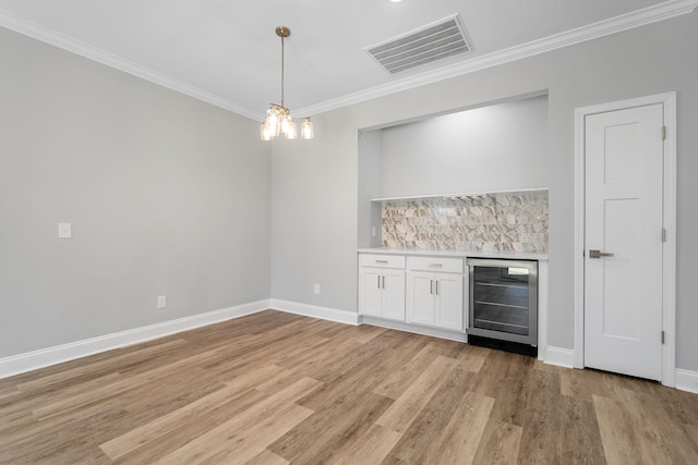 bar featuring crown molding, white cabinetry, wine cooler, light hardwood / wood-style floors, and decorative light fixtures