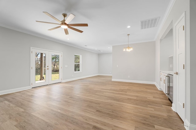 unfurnished living room with french doors, crown molding, ceiling fan with notable chandelier, and light hardwood / wood-style flooring