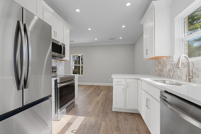 kitchen with white cabinetry, sink, stainless steel appliances, and a healthy amount of sunlight