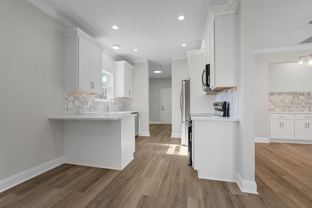 kitchen featuring crown molding, stainless steel appliances, hardwood / wood-style flooring, and white cabinets