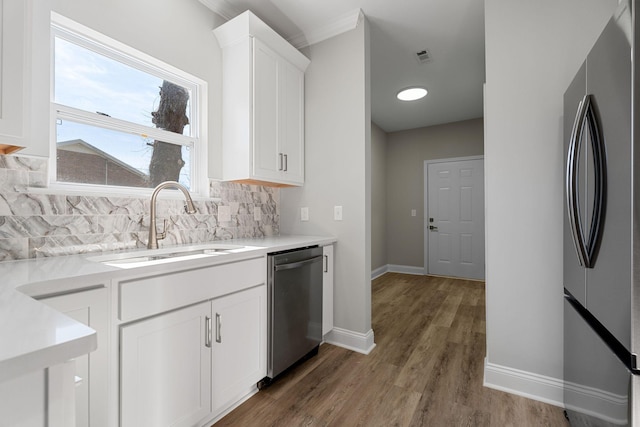 kitchen with sink, white cabinetry, tasteful backsplash, hardwood / wood-style flooring, and stainless steel appliances