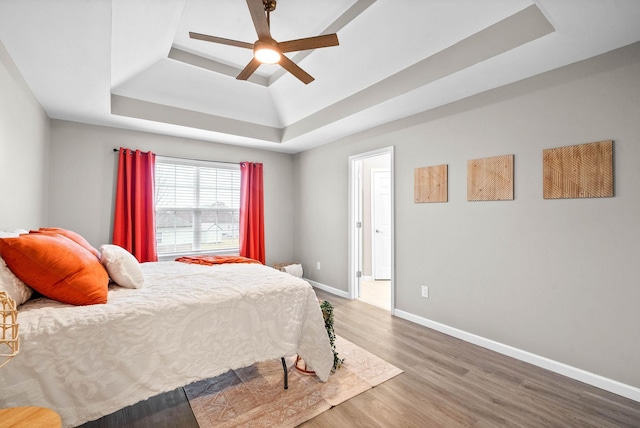 bedroom with hardwood / wood-style floors, a tray ceiling, and ceiling fan