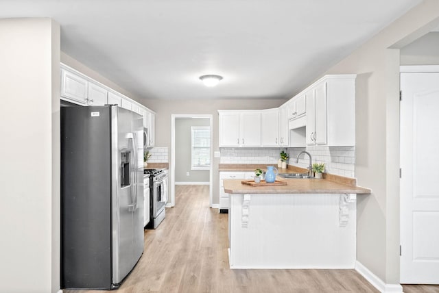 kitchen with white cabinetry, appliances with stainless steel finishes, sink, and kitchen peninsula