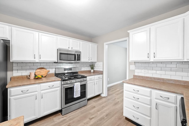 kitchen featuring backsplash, stainless steel appliances, light hardwood / wood-style flooring, and white cabinets