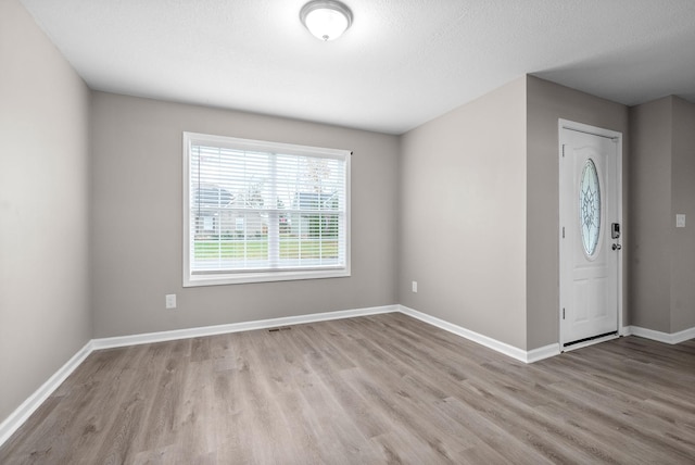 entrance foyer with light hardwood / wood-style flooring and a textured ceiling