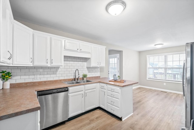 kitchen with sink, stainless steel appliances, white cabinets, decorative backsplash, and kitchen peninsula