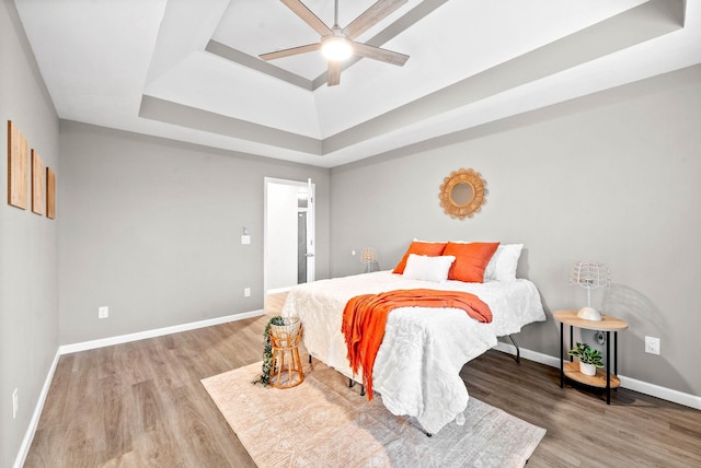 bedroom featuring ceiling fan, a raised ceiling, and hardwood / wood-style floors