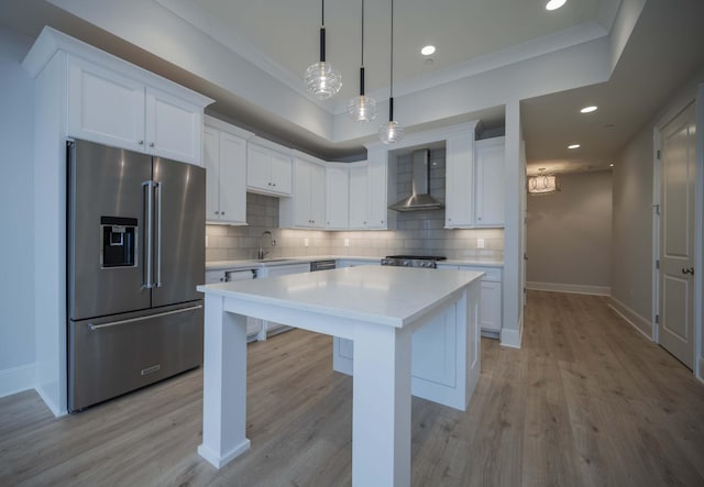 kitchen featuring white cabinetry, a center island, high end fridge, and wall chimney exhaust hood