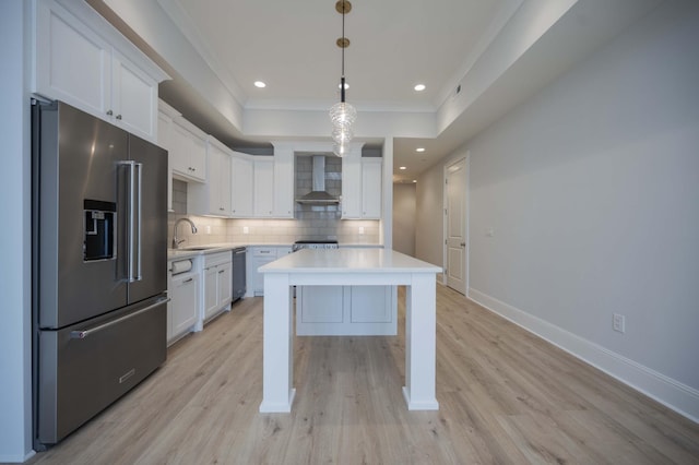 kitchen with wall chimney exhaust hood, white cabinetry, pendant lighting, stainless steel appliances, and decorative backsplash