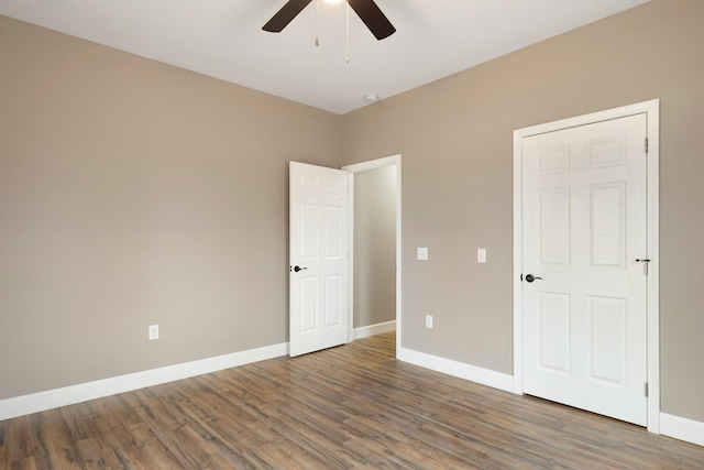 unfurnished bedroom featuring dark wood-style floors, baseboards, and a ceiling fan