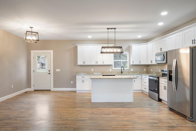 kitchen with stainless steel appliances, a center island, white cabinetry, hanging light fixtures, and light stone countertops