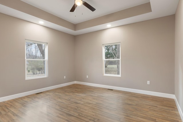 empty room featuring recessed lighting, plenty of natural light, baseboards, and wood finished floors