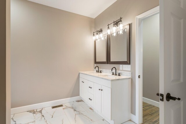 bathroom featuring visible vents, a sink, baseboards, and double vanity