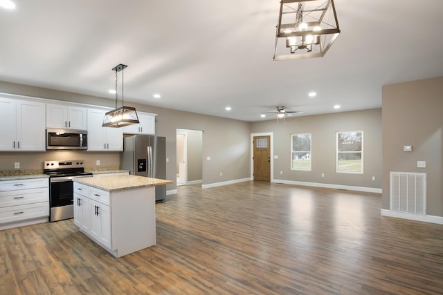 kitchen featuring pendant lighting, visible vents, appliances with stainless steel finishes, open floor plan, and white cabinets