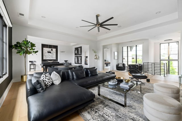 living room with a raised ceiling and light hardwood / wood-style flooring