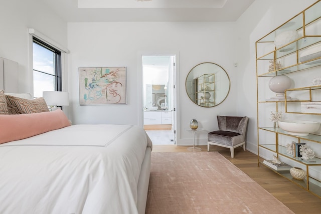 bedroom with hardwood / wood-style flooring and ensuite bath