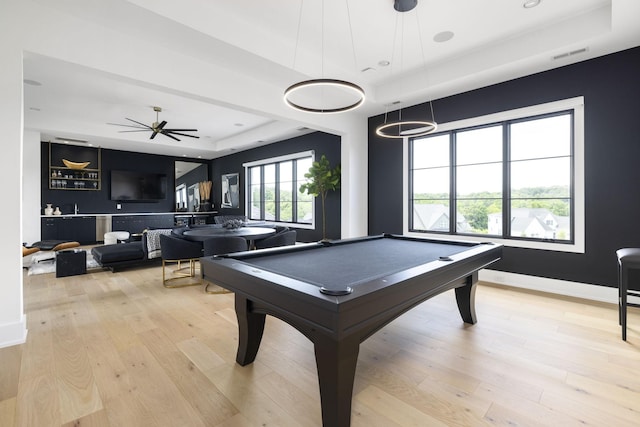 game room featuring a tray ceiling, pool table, ceiling fan, and light wood-type flooring