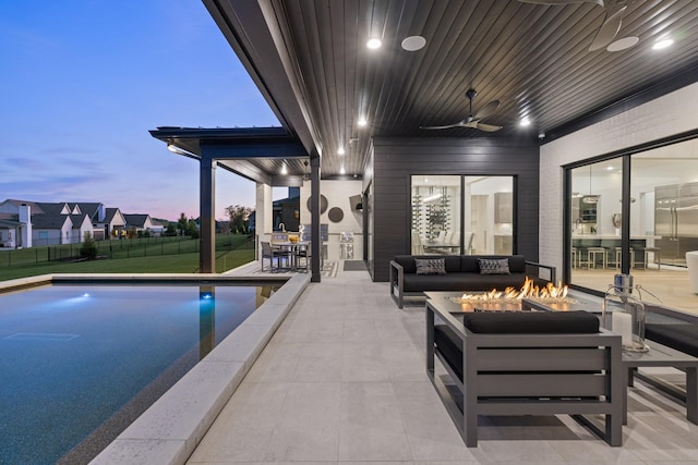 pool at dusk with an outdoor living space with a fire pit, ceiling fan, and a patio area