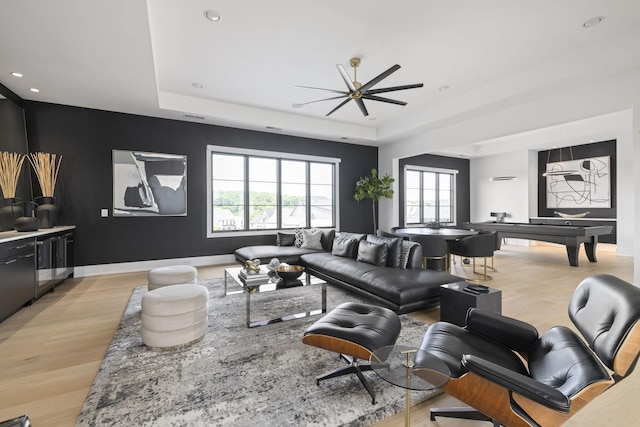 living room with a tray ceiling and light hardwood / wood-style floors