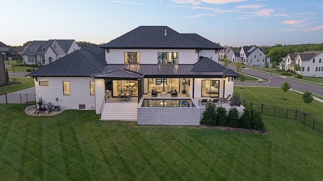 back house at dusk with an outdoor living space, a yard, a swimming pool, and a patio area