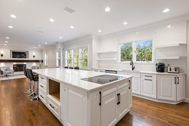 kitchen with sink, white cabinetry, black electric cooktop, dark hardwood / wood-style floors, and a kitchen island