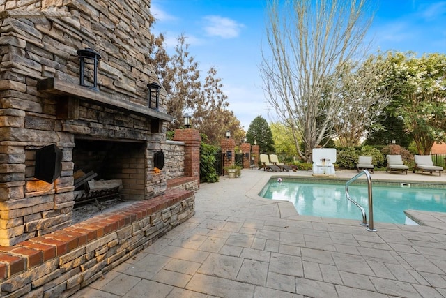 view of pool featuring a patio and an outdoor stone fireplace