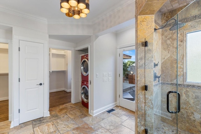 bathroom featuring an enclosed shower, crown molding, plenty of natural light, and stacked washing maching and dryer