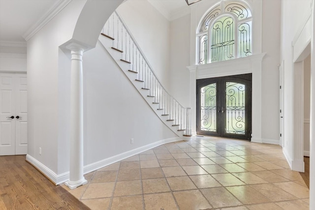 entryway featuring crown molding, a wealth of natural light, french doors, and a towering ceiling