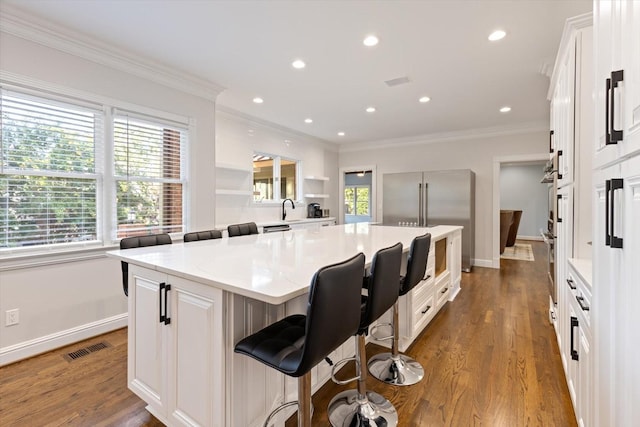 kitchen featuring a kitchen island, dark wood-type flooring, a breakfast bar area, and white cabinets