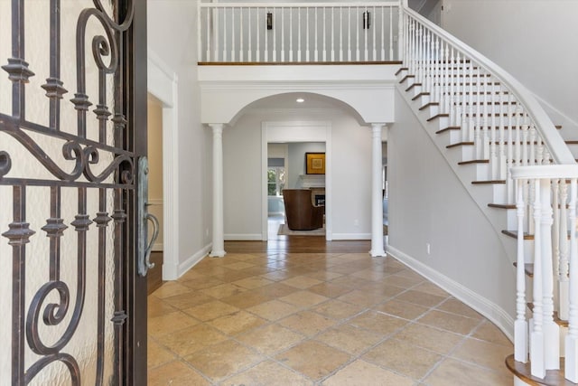 foyer with crown molding, decorative columns, and a high ceiling