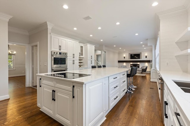 kitchen with light stone counters, stainless steel appliances, a kitchen island, and white cabinets