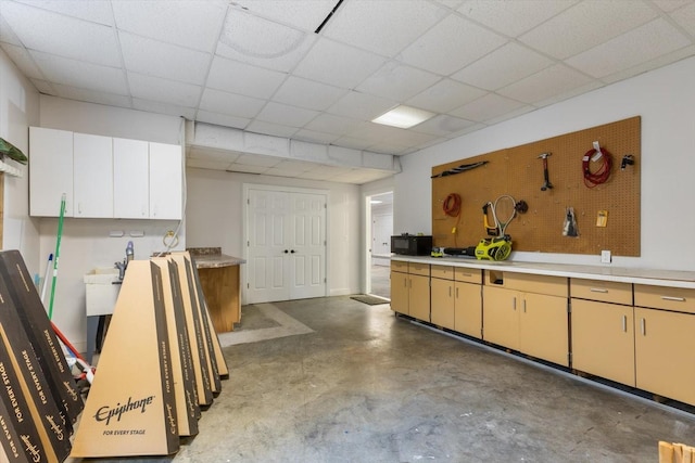 kitchen with a paneled ceiling and concrete floors