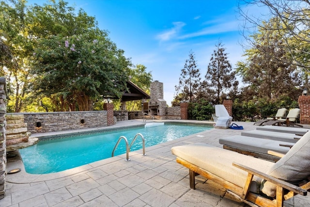 view of pool with a patio and an outdoor stone fireplace