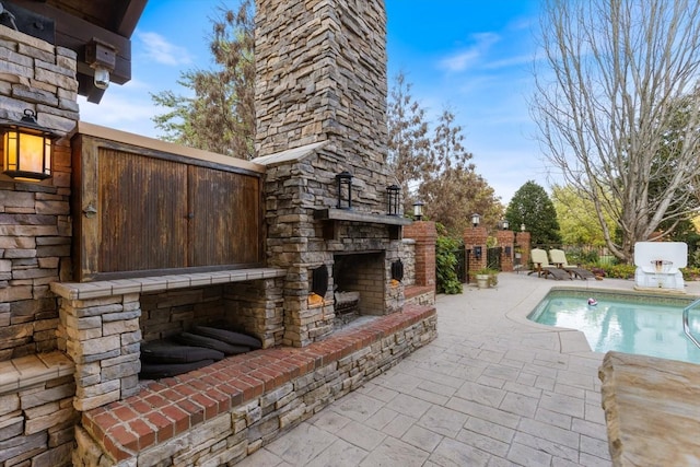 view of swimming pool with a patio and an outdoor stone fireplace