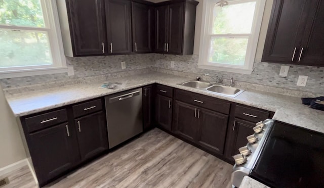 kitchen with sink, range, light hardwood / wood-style flooring, stainless steel dishwasher, and backsplash