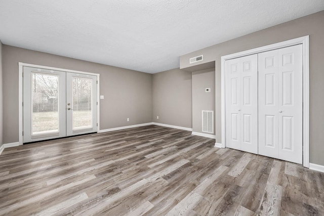 unfurnished bedroom with access to exterior, french doors, a textured ceiling, and light wood-type flooring