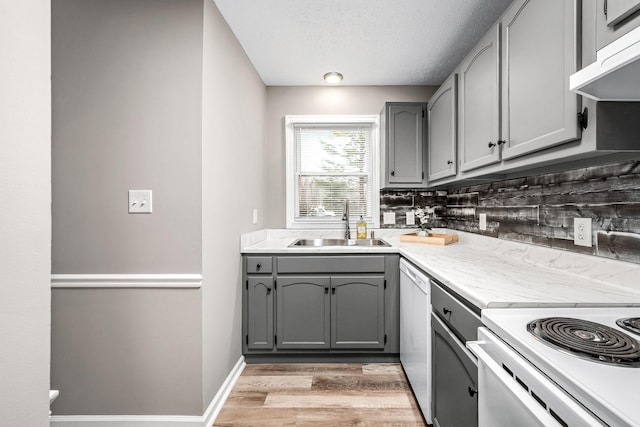 kitchen with sink, gray cabinetry, white dishwasher, extractor fan, and light wood-type flooring