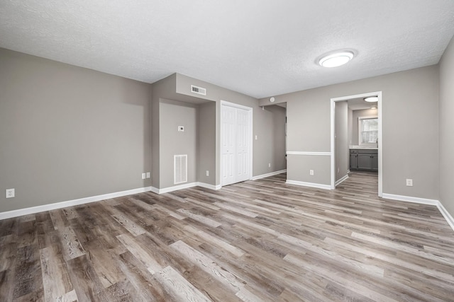 spare room featuring a textured ceiling and light hardwood / wood-style floors