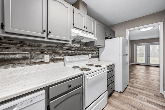 kitchen with gray cabinets, light wood-type flooring, white appliances, and decorative backsplash