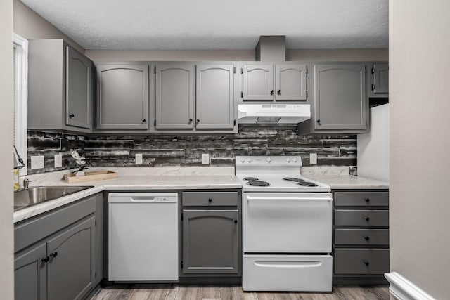 kitchen featuring gray cabinetry, backsplash, hardwood / wood-style flooring, a textured ceiling, and white appliances