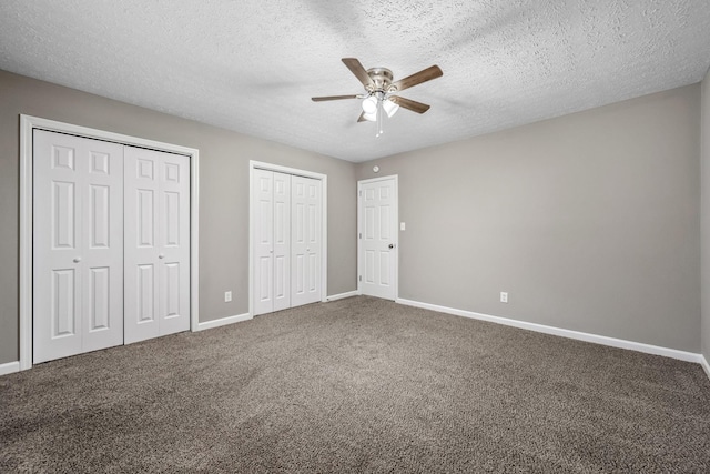 unfurnished bedroom featuring ceiling fan, carpet flooring, two closets, and a textured ceiling