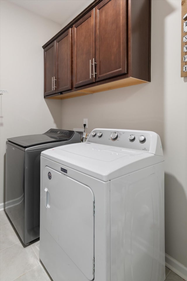 laundry room with cabinets, washing machine and dryer, and light tile patterned floors