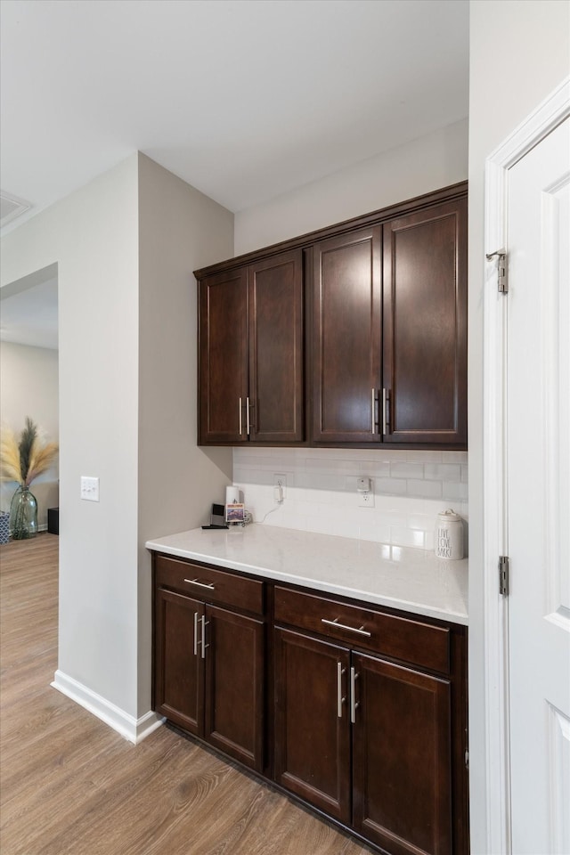 interior space featuring dark brown cabinetry, hardwood / wood-style floors, and decorative backsplash