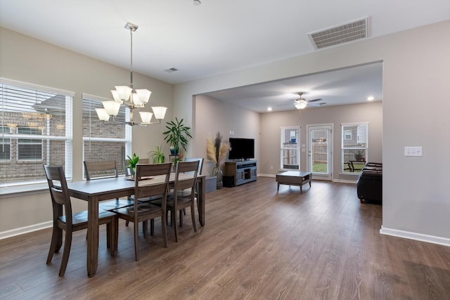 dining room with ceiling fan with notable chandelier and dark wood-type flooring